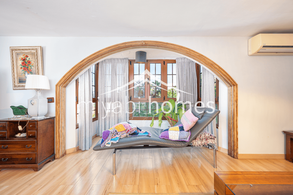Gemütliches Wohnzimmer mit Bogenfenster und Blick nach draußen.