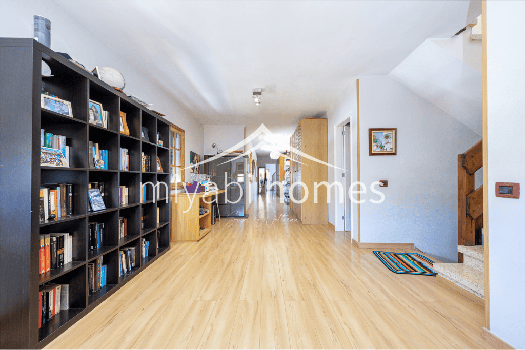 Geräumiges Wohnzimmer mit Bücherregal und Holzfußboden in Miyabi Homes.