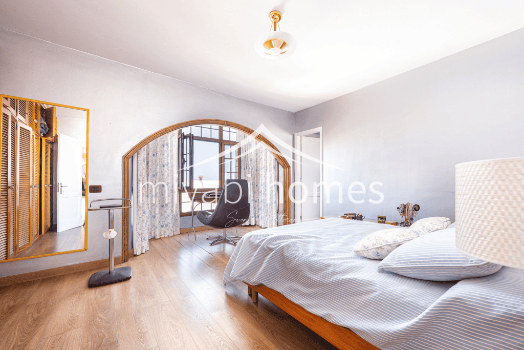 Gemütliches Schlafzimmer mit großem Fenster und Blick auf die Berge.