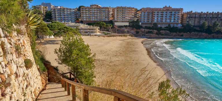 Escalera a playa urbana con edificios al fondo.
