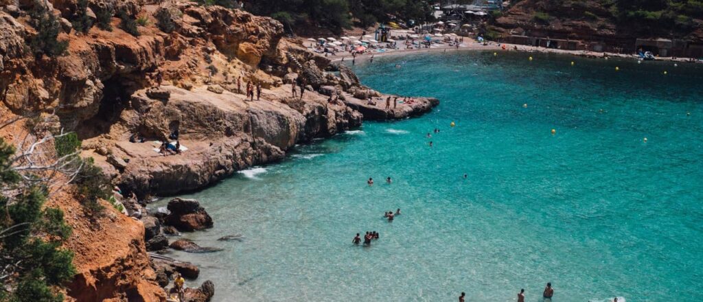 Playa con agua cristalina y rocas en la costa.