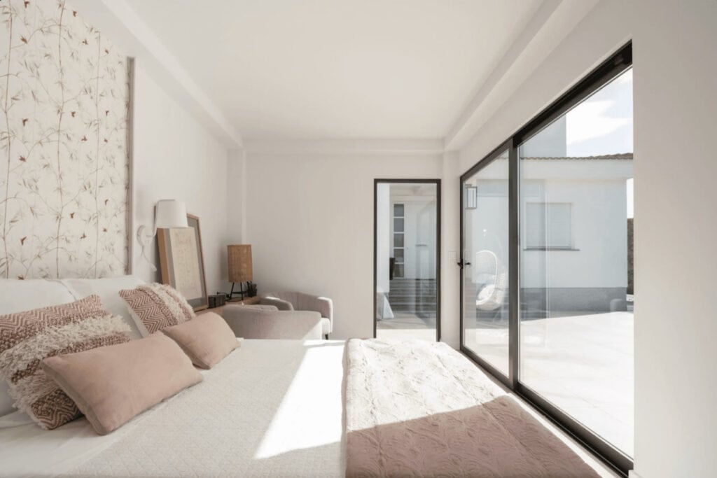 Habitación luminosa con cama y ventanales grandes.