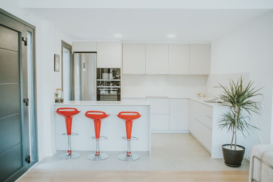 Moderna cocina blanca con taburetes rojos