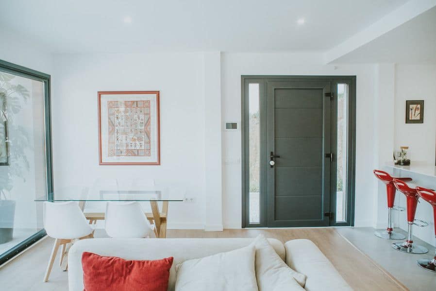 Moderno salón con puerta negra y sillas rojas