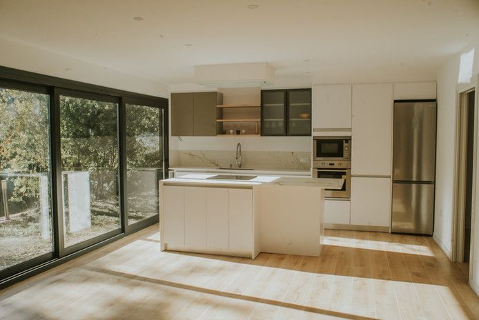 Cocina moderna con isla central y ventanales grandes.