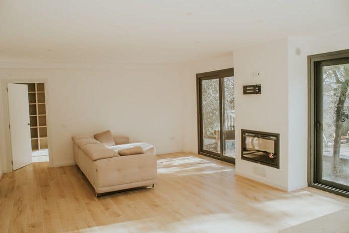Salón moderno con sofá, chimenea y ventanas grandes.