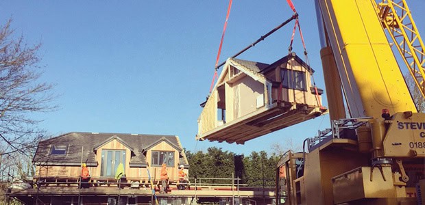 Crane lifting a moduloft build onto a house.