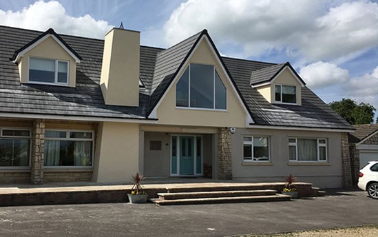 Contemporary house with loft extension and large windows in a residential area.