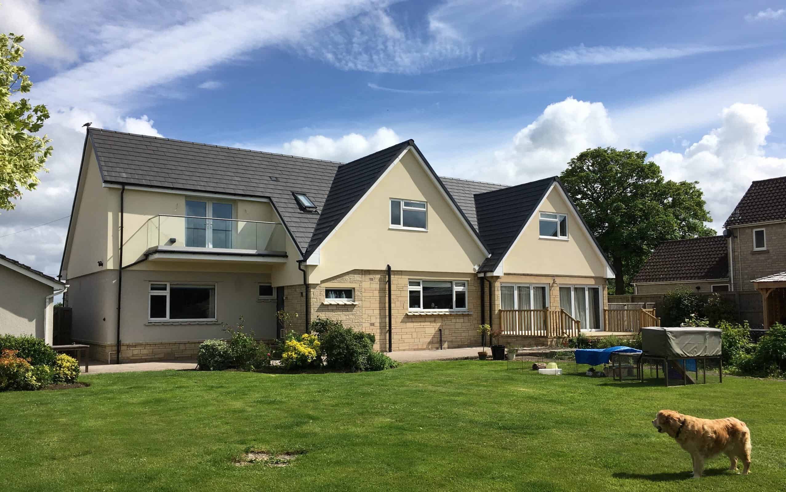 Modern detached house with a large garden and blue sky in the background.