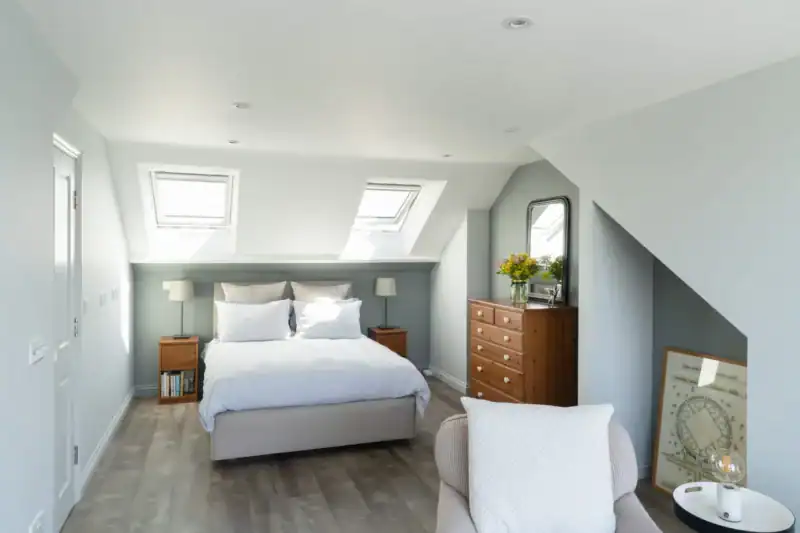 Bright attic bedroom with skylights and modern decor for loft conversion.