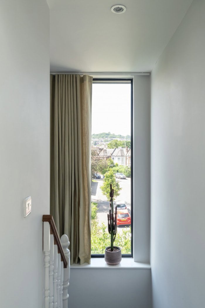 Bright interior window with beige curtain and view of neighbourhood.