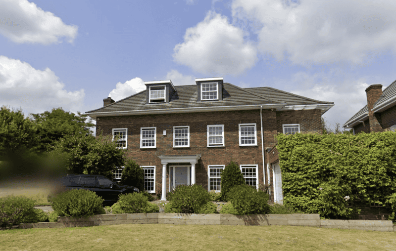 Large brick house with multiple windows and a well-maintained garden.
