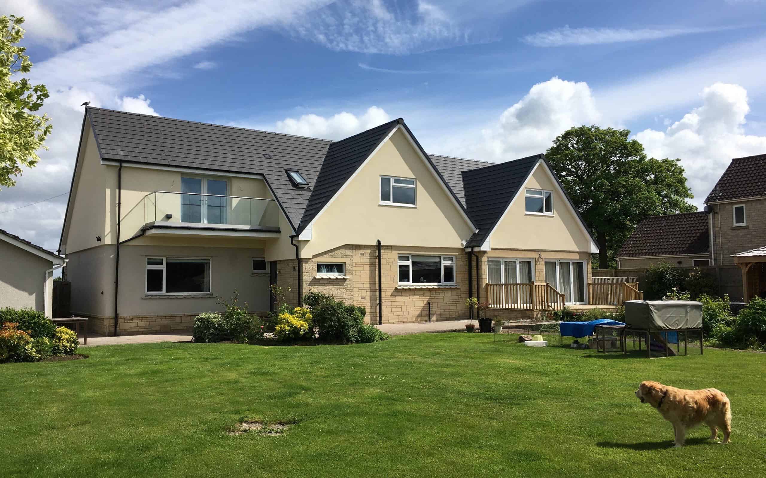 Modern detached house with a large garden and balcony, under a blue sky.