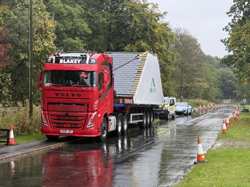 Large red Volvo truck transporting a module from the factory to site ready to be installed.