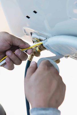 Man is installing wall compressor of air conditioner during hot season