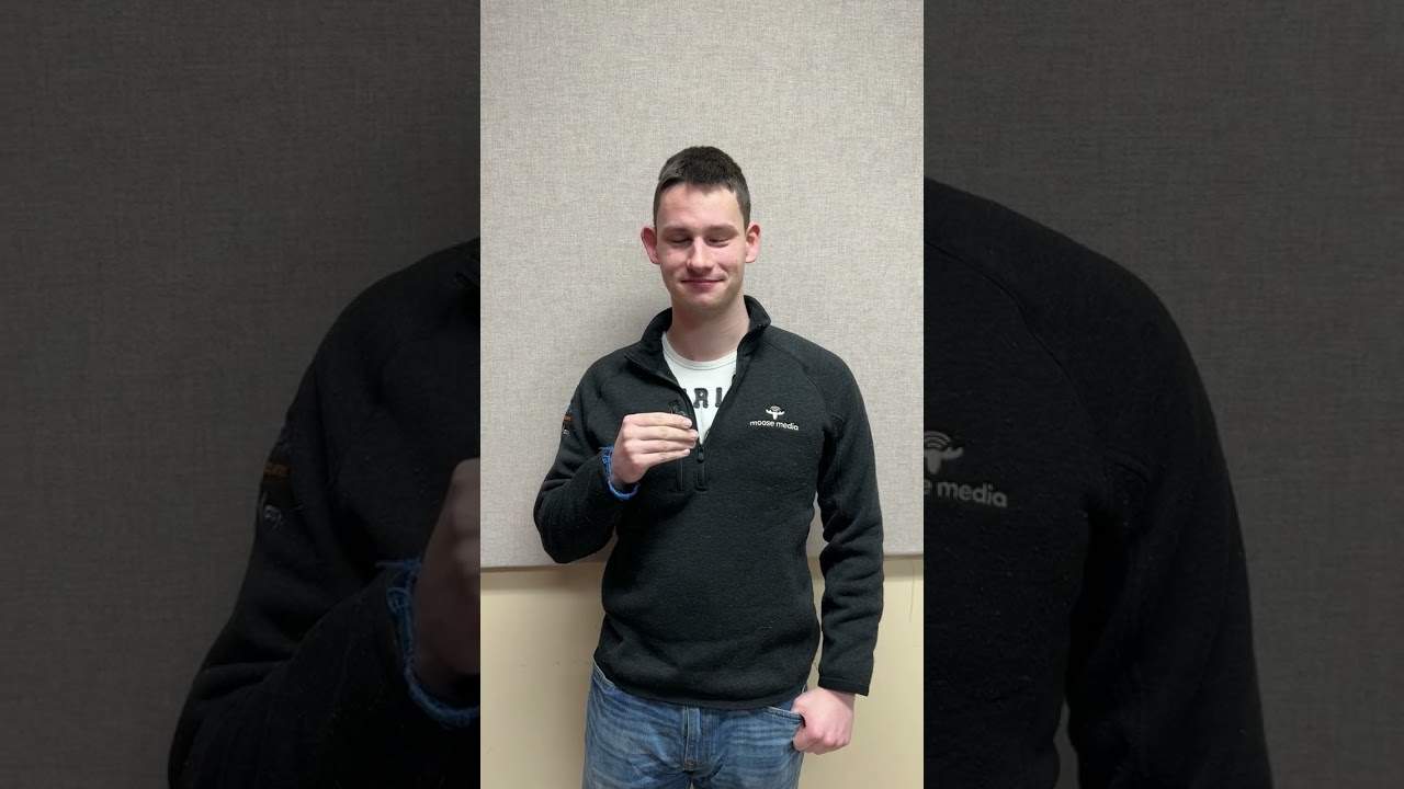 Young man wearing Moose Media branded fleece jacket at indoor event.