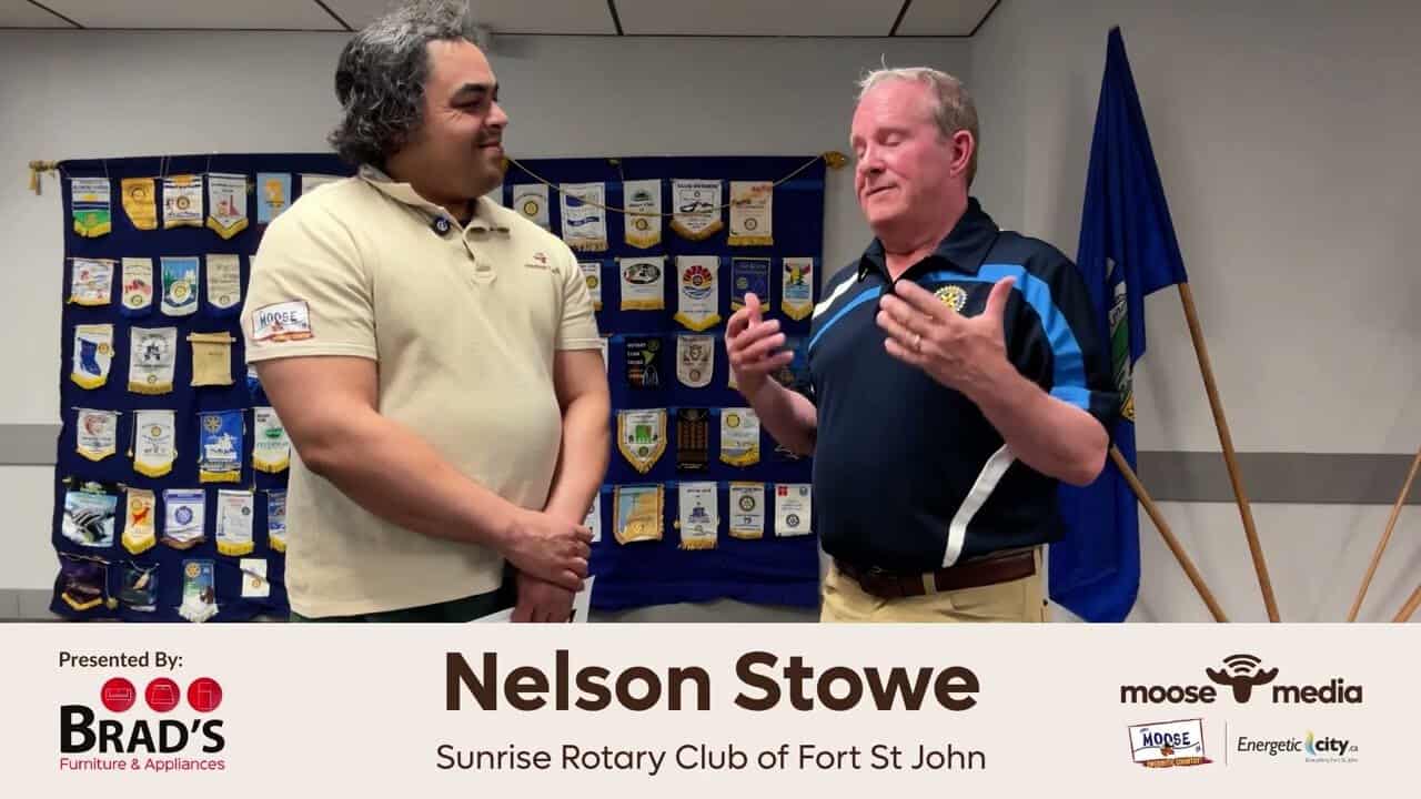 Young man and older man conversing at Rotary Club meeting, showcasing community engagement and leadership.