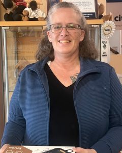 Smiling woman wearing glasses in a blue jacket at MooseMedia FSJ.