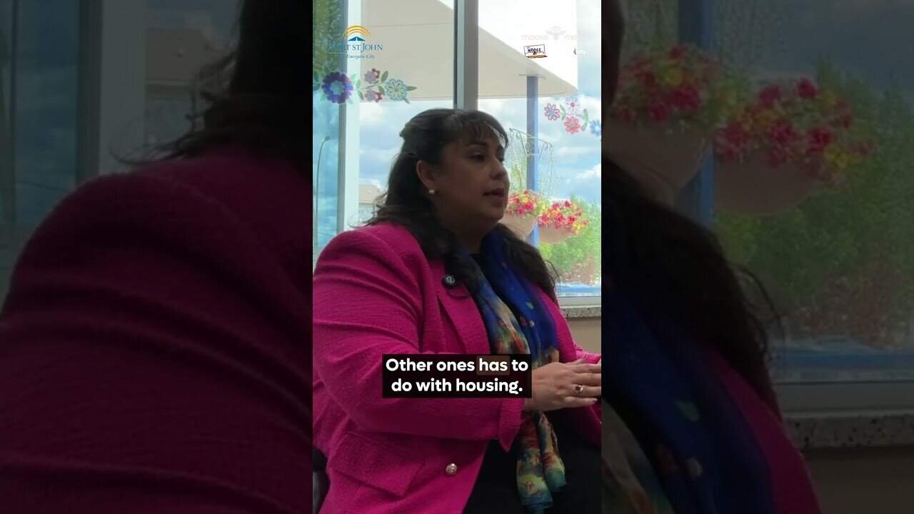 Woman in pink blazer discussing housing issues at Moose Media FSJ.