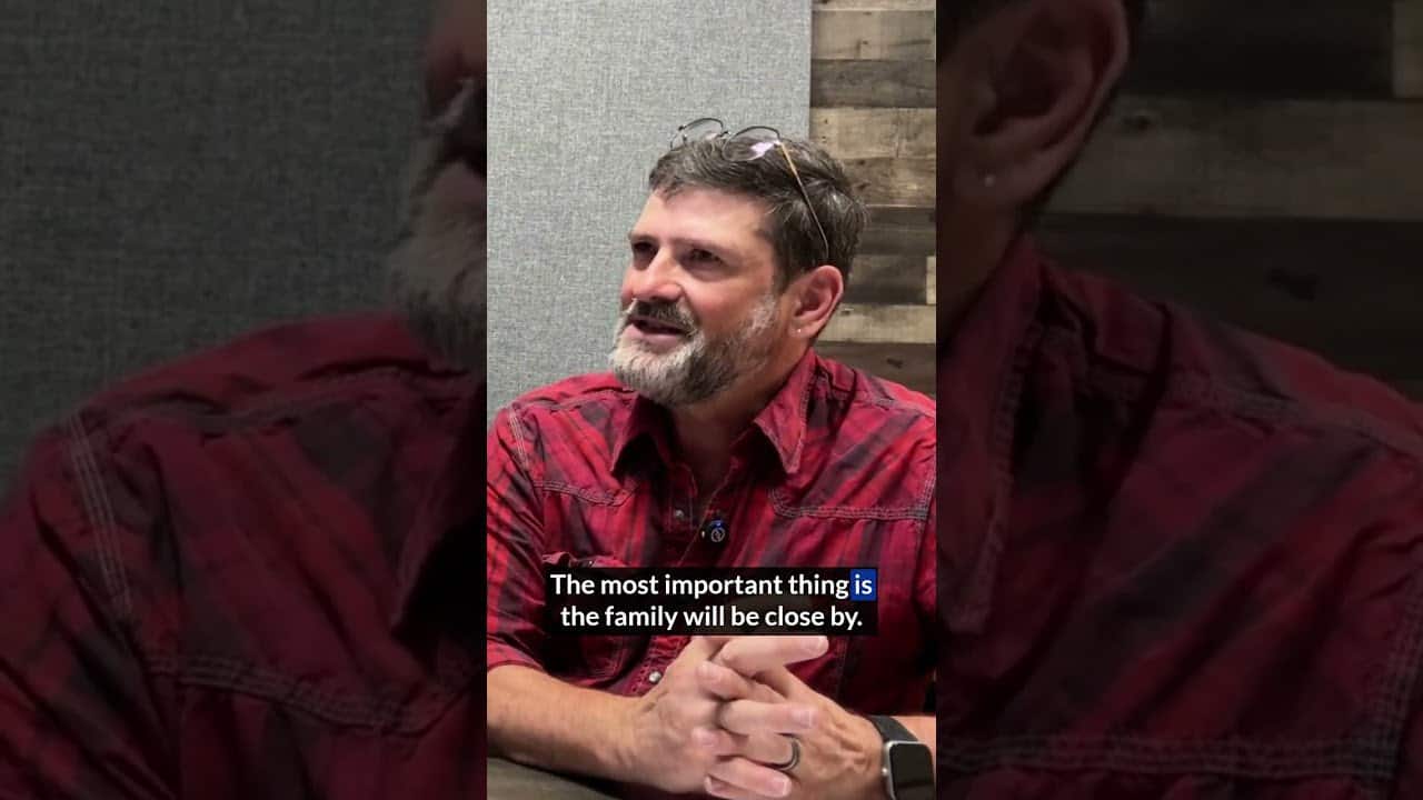 Man in red plaid shirt speaking about family importance.