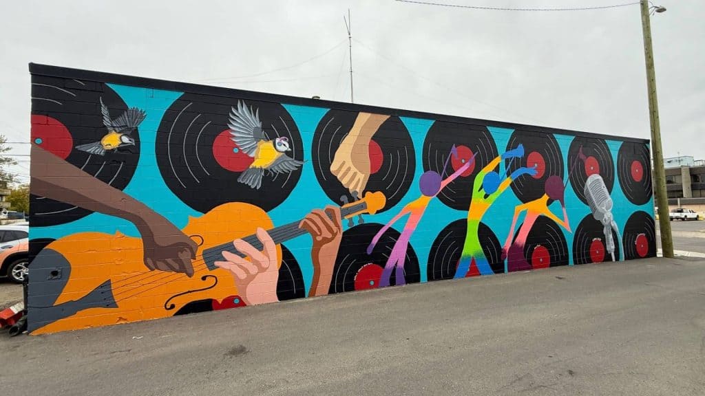 Colorful mural featuring musicians, birds, and dance figures on a brick wall in Moose Jaw, Saskatchewan.
