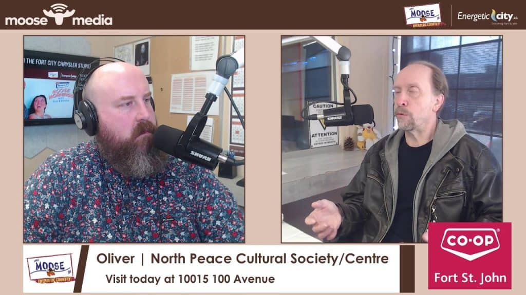 Two men speaking into microphones during a radio interview at North Peace Cultural Centre.