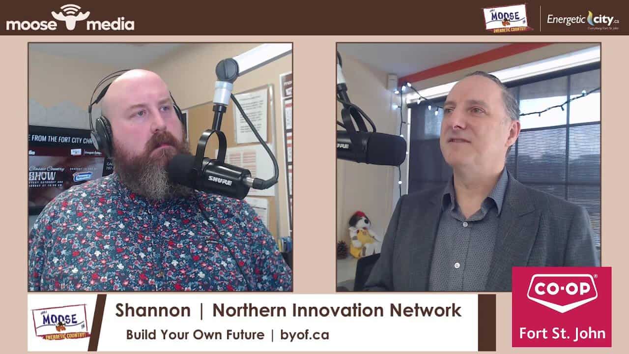 Two men speaking into microphones during a podcast interview.