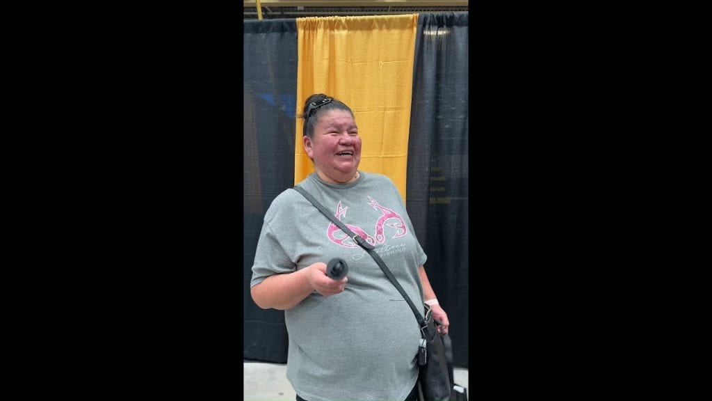 Woman speaking at MooseMedia event, holding a microphone, smiling.
