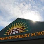 North Peace Secondary School building with bright sky and sunburst.