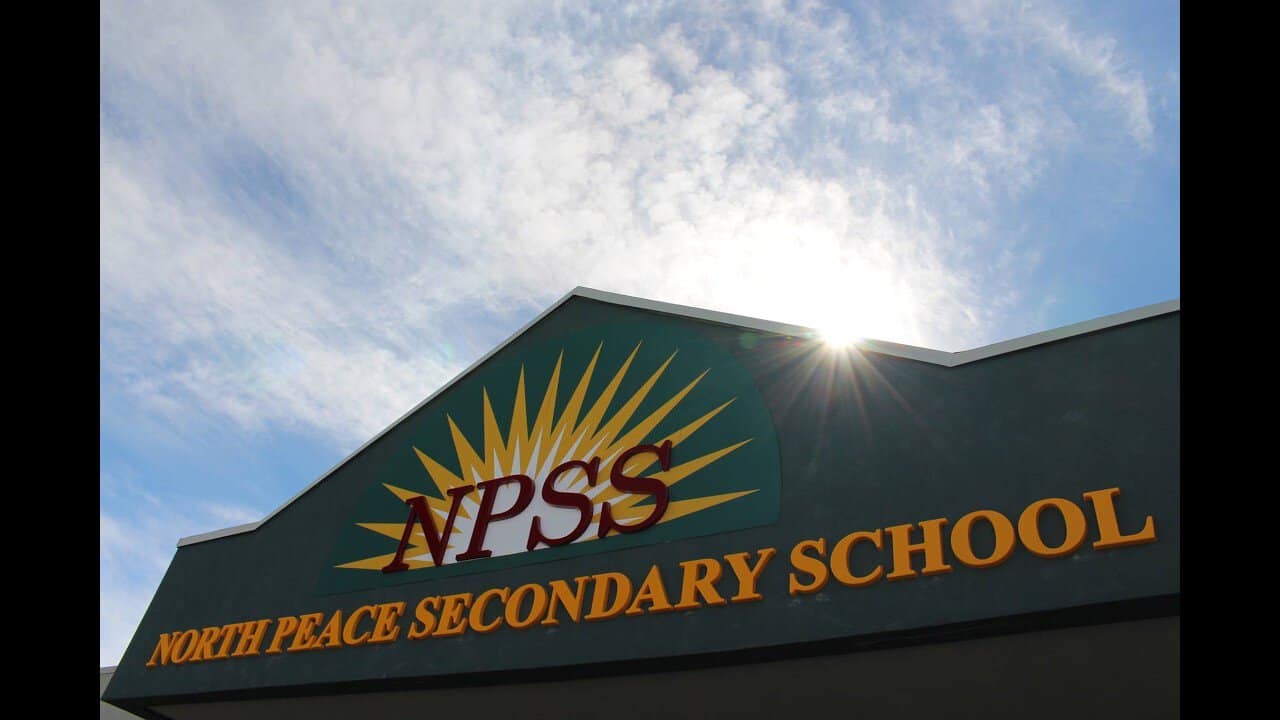 North Peace Secondary School building with bright sky and sunburst.