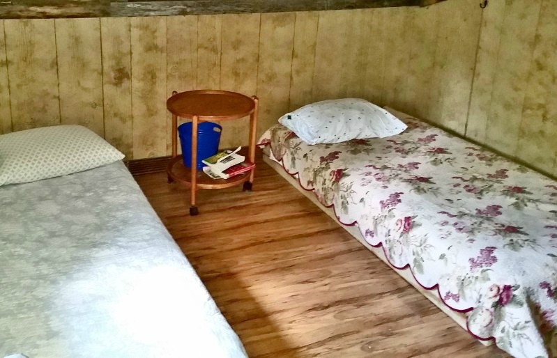 Cozy mountain cabin bedroom with rustic wooden walls and twin beds, perfect for a mountain getaway.