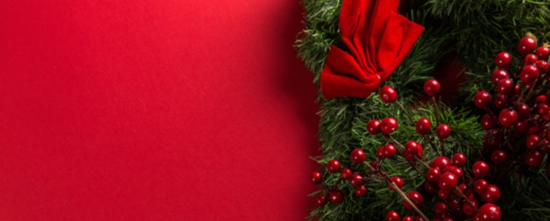 Festive Christmas wreath with red berries and a red bow at Mountain Harbour holiday resort, perfect for seasonal celebrations and relaxing getaways.