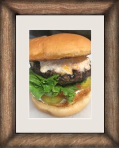 Grilled cheeseburger with lettuce, tomato, pickles, and melted cheese on a toasted bun.