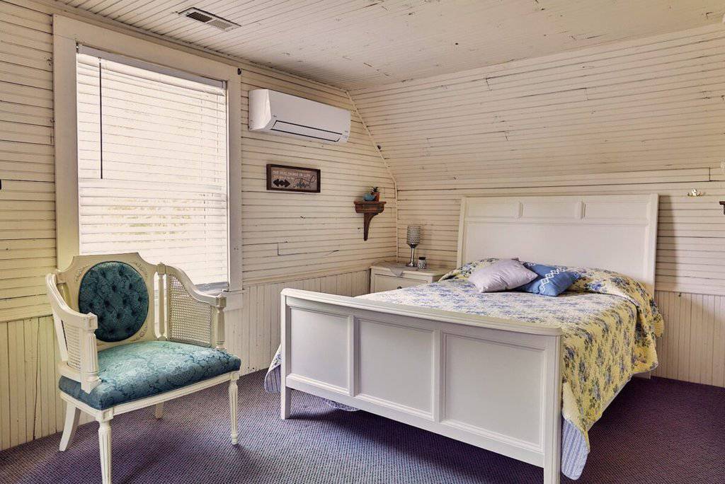 Cozy mountain retreat bedroom with wooden walls, white furnishings, and a serene ambiance at Mountain Harbour.