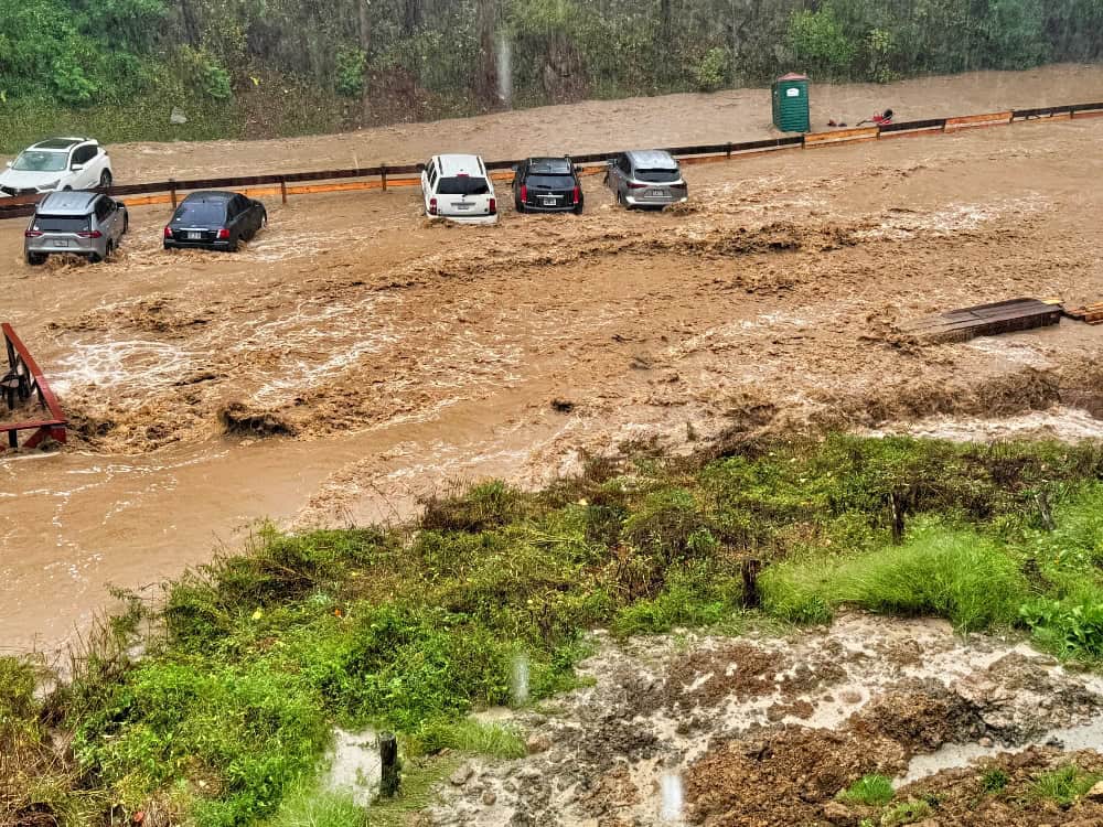 Flooded parking lot during heavy rain at Mountain Harbour, causing water damage to vehicles.