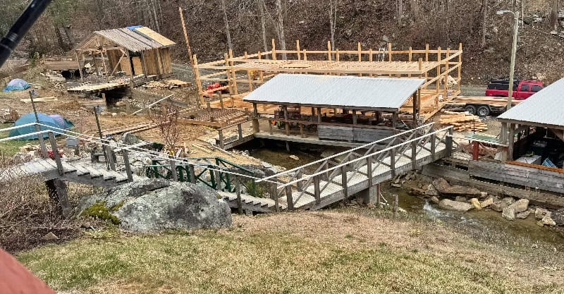 Mountain harbour construction site with wooden bridges and structures, scenic outdoor mountain setting.