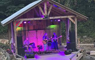 Outdoor mountain venue with a stage hosting a live band performance at Mountain Harbour.