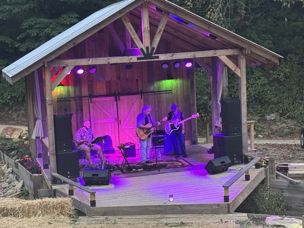 Outdoor mountain venue with a stage hosting a live band performance at Mountain Harbour.