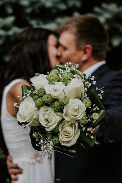White rose wedding bouquet with green accents and pearl details.