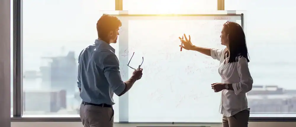 Fractional CMO and CEO developing a go-to-market strategy on a whiteboard during a marketing leadership engagement.