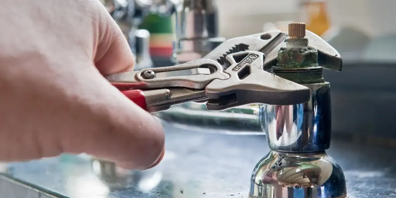Plumber-Using-Pliers-To-Repair-Kitchen-Faucet