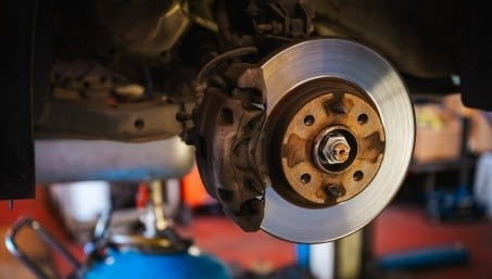 Close-up of a car brake disc and caliper during repair.