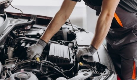 Technician inspecting car engine at Murdock & Son Automotive.