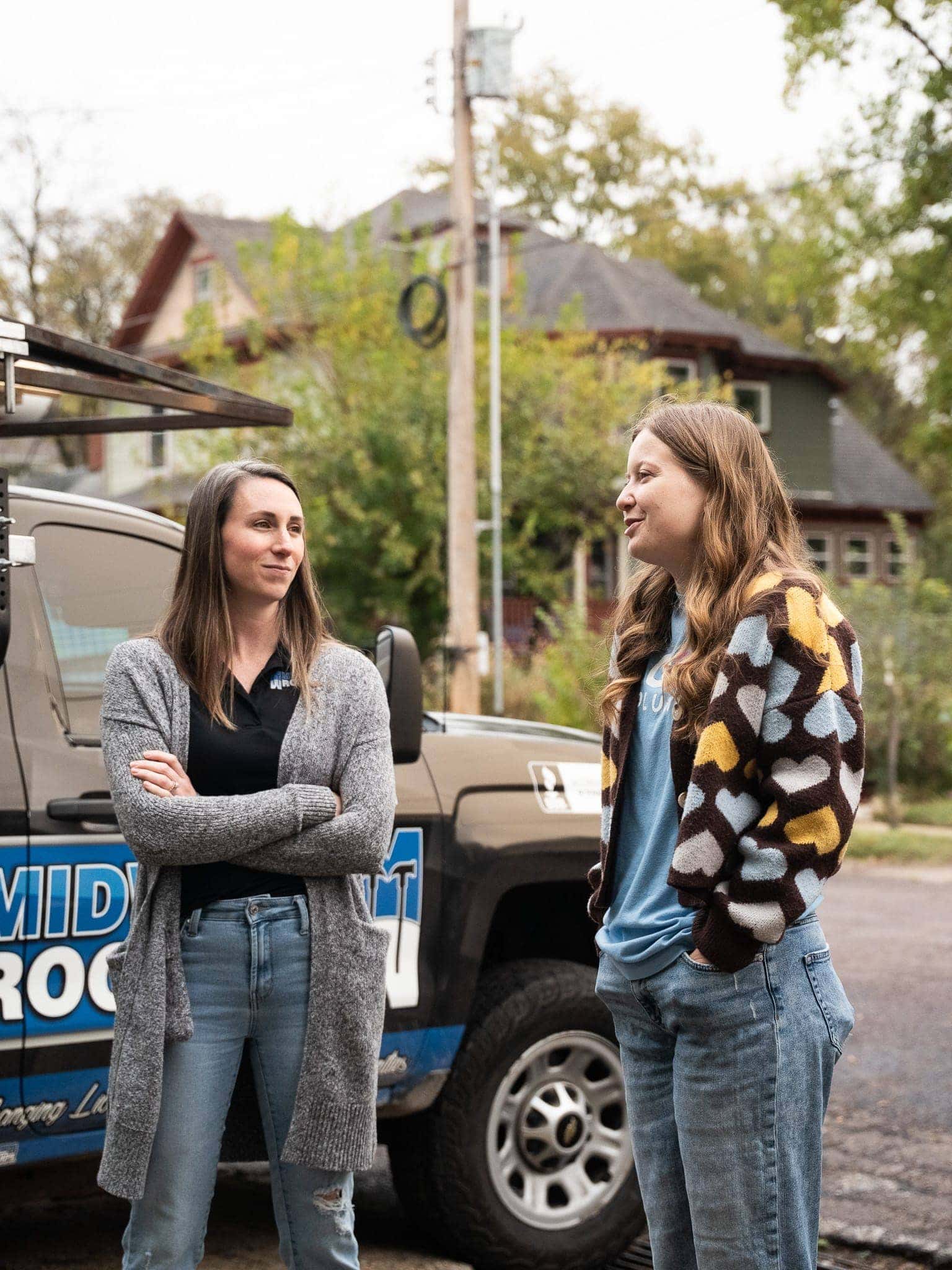 Friendly conversation about roofing services outside residential property.