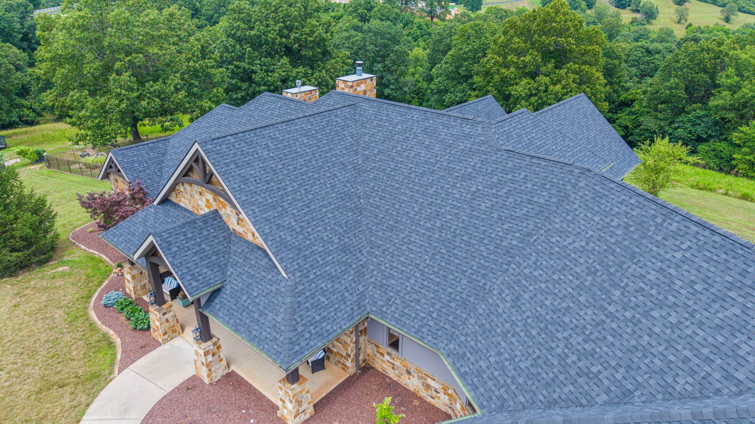 Beautiful residential roof with durable asphalt shingles in a lush green setting.