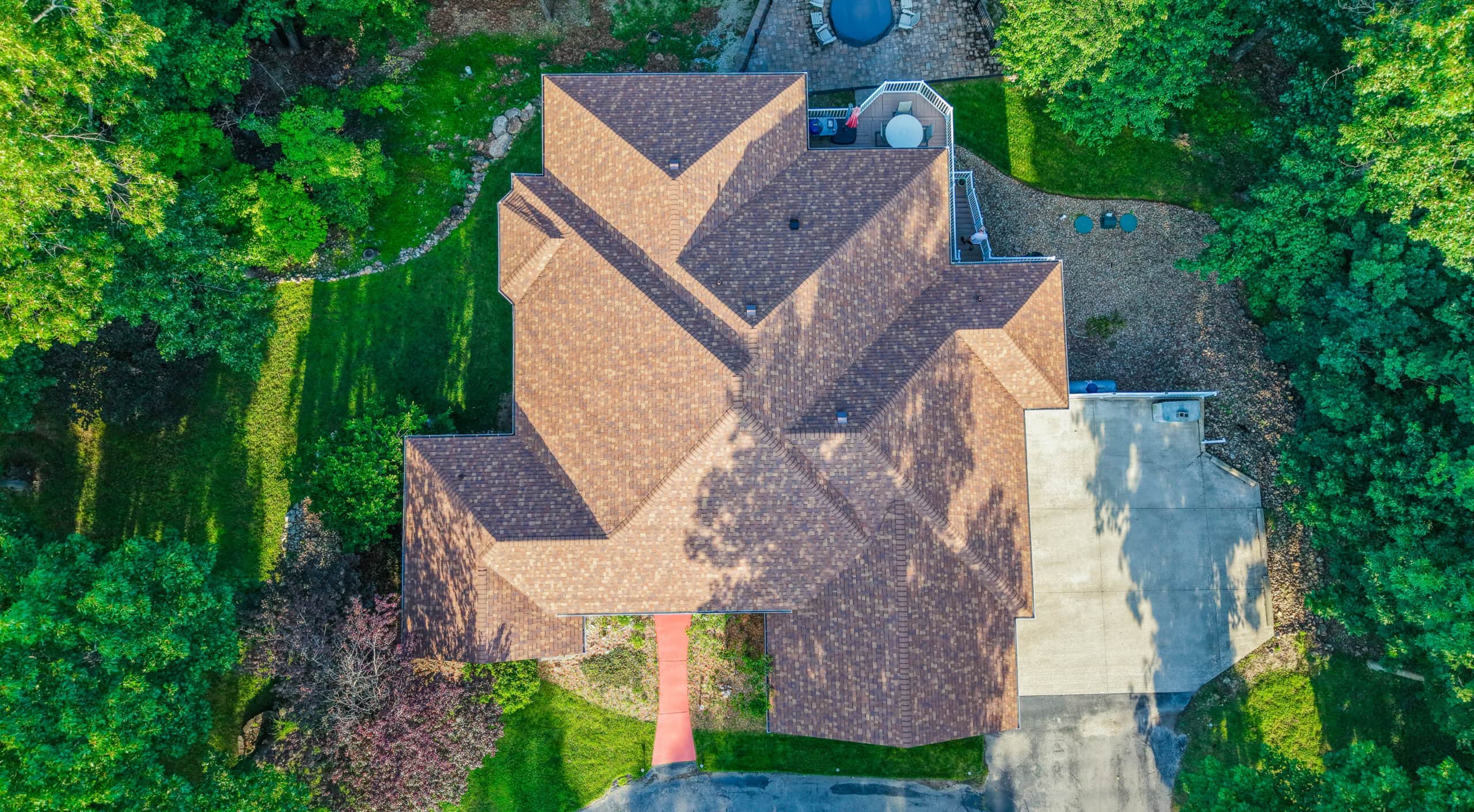 Aerial view of a residential roof showcasing durable roofing shingles in a lush green neighborhood.