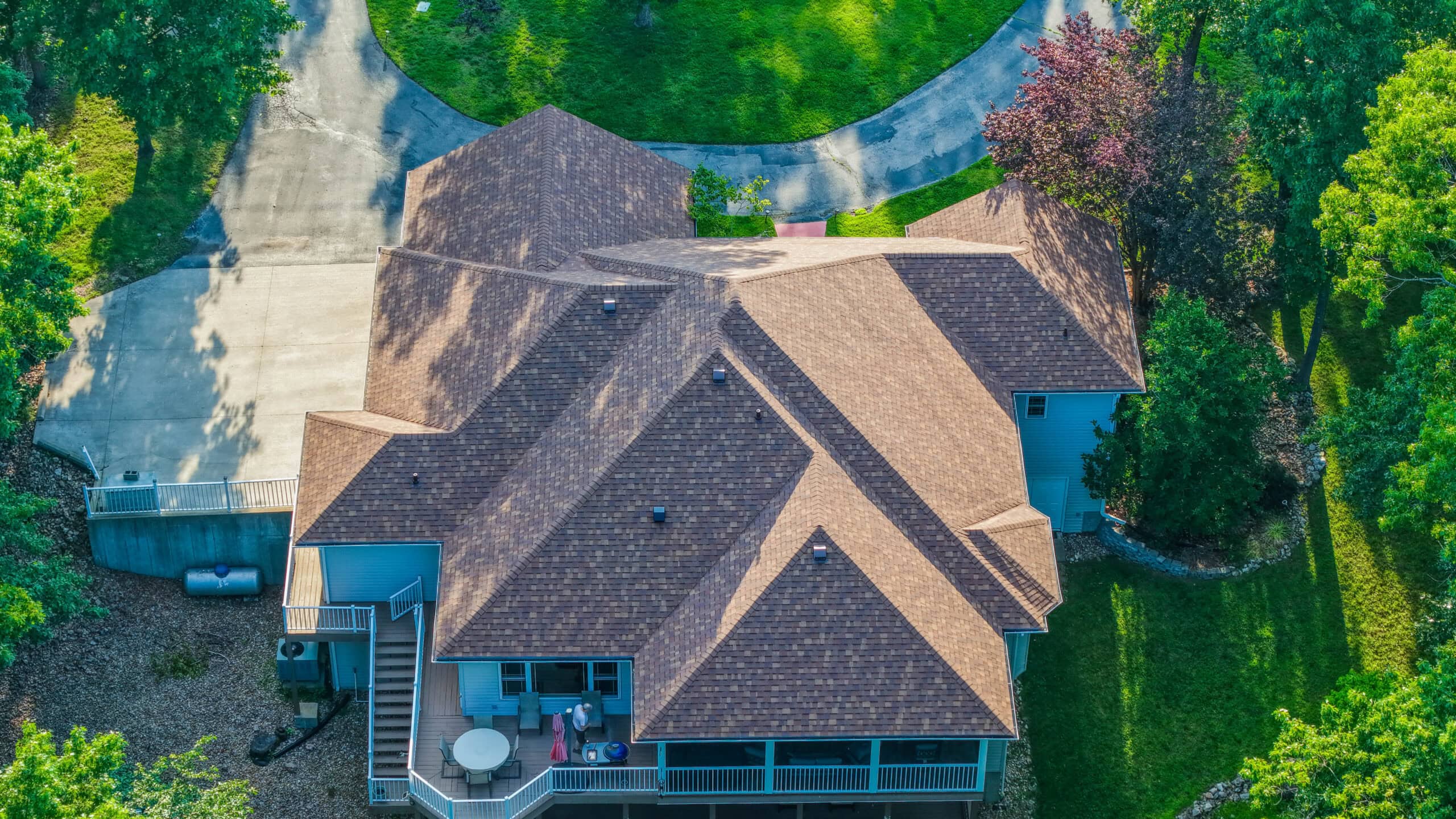 Aerial view of a residential house with new roofing in a lush neighborhood.