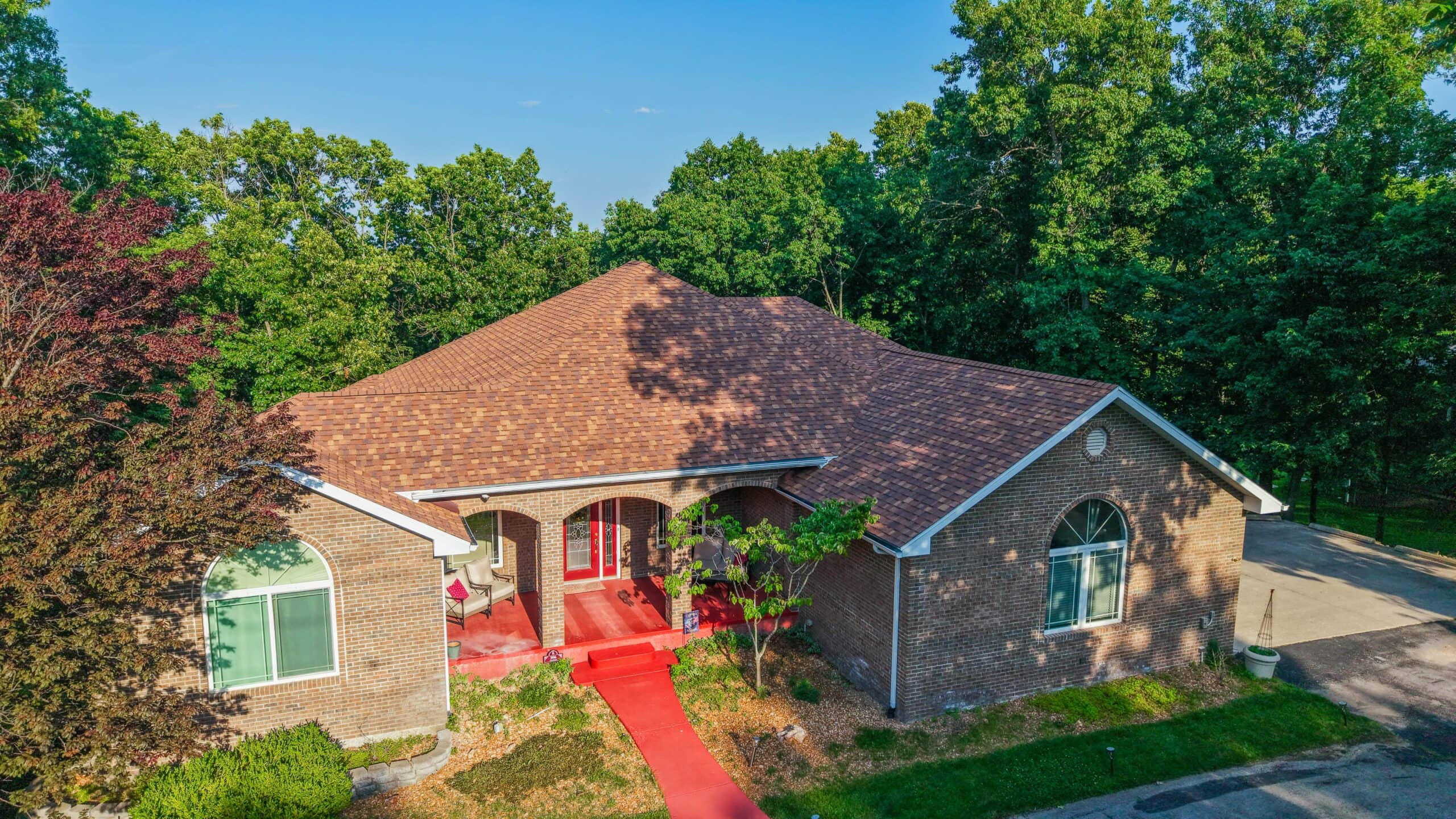 A beautiful residential home with a new asphalt shingle roof in a lush green neighborhood.