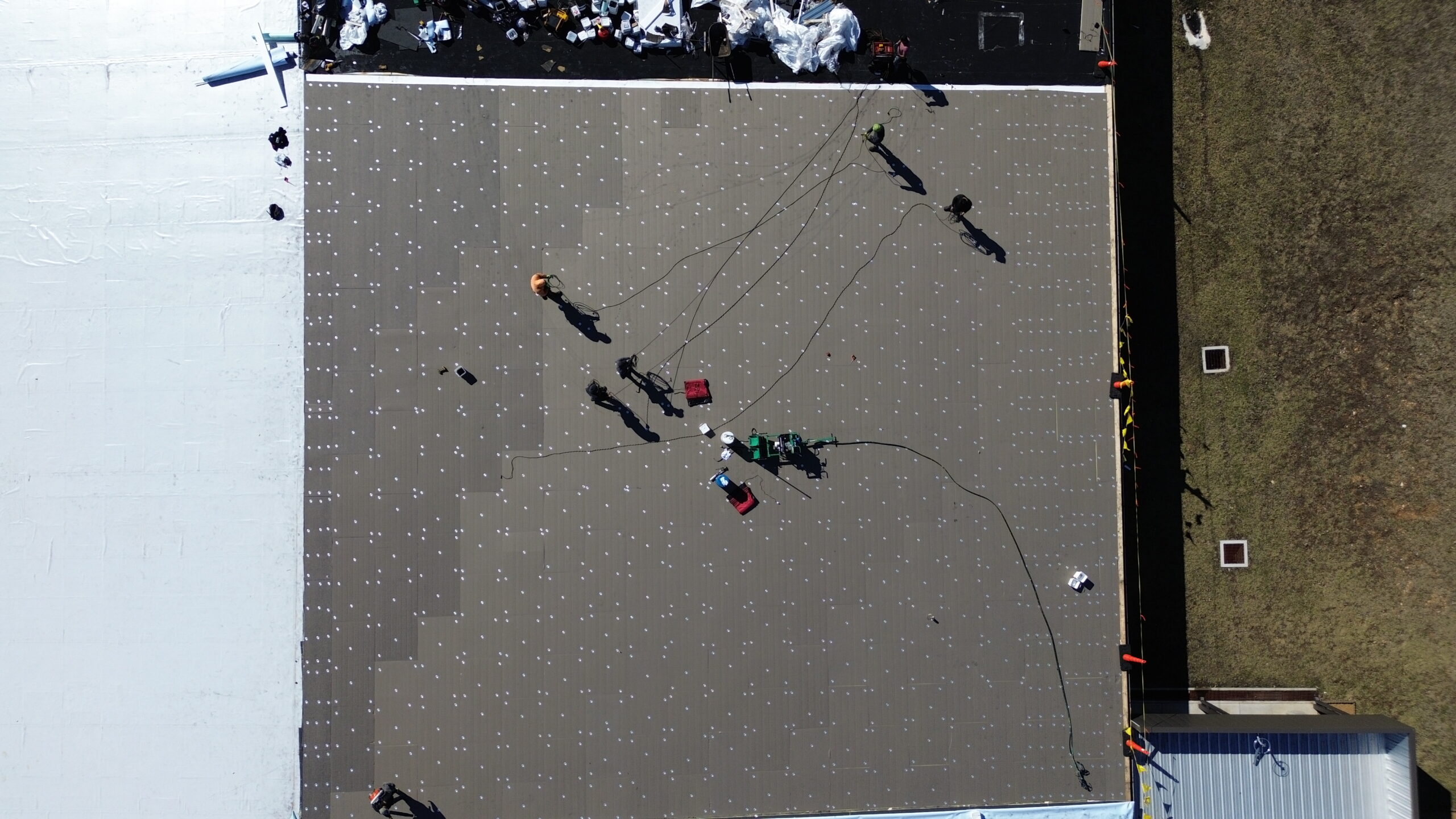 Commercial roofing installation with workers on a flat roof, focusing on roofing services in Midwest.