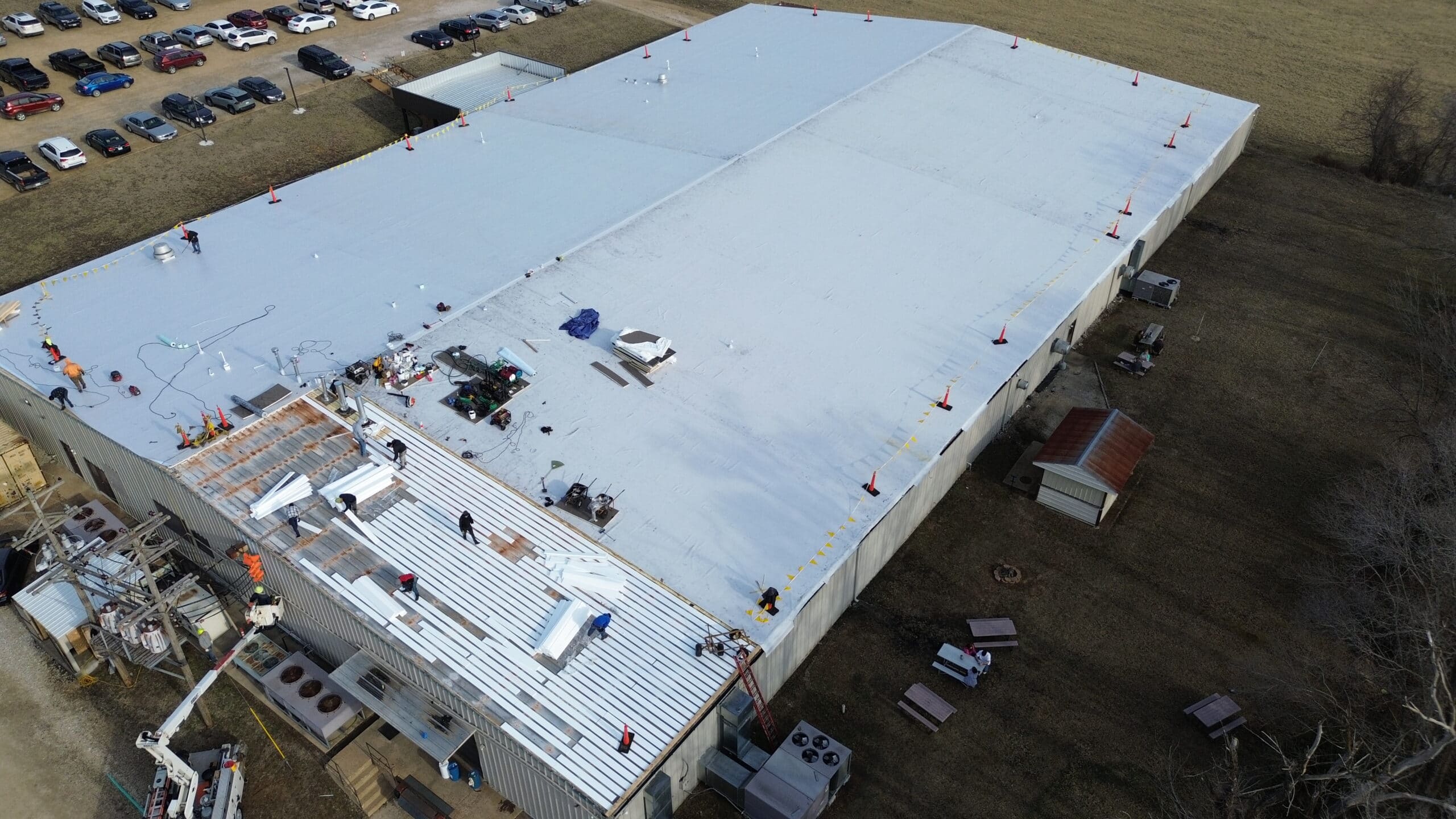 Commercial roofing installation with workers on a flat roof.